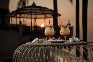 A table with two cocktails, a small dish, and a glass of water. - Villa Dei Melograni Boutique Hotel (Cefalù)