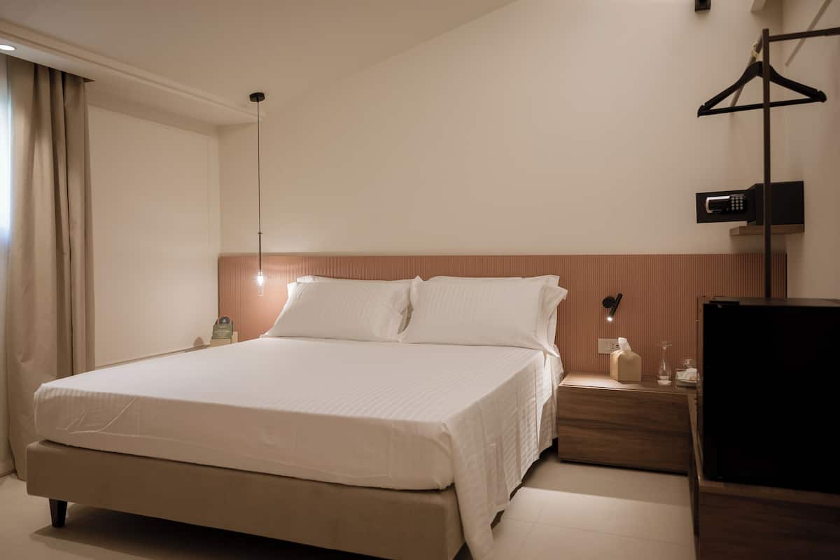 Habitación de hotel con una cama grande, mesitas de noche, un televisor y un armario.
