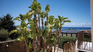 Un balcón con vista al mar, rodeado de palmeras.