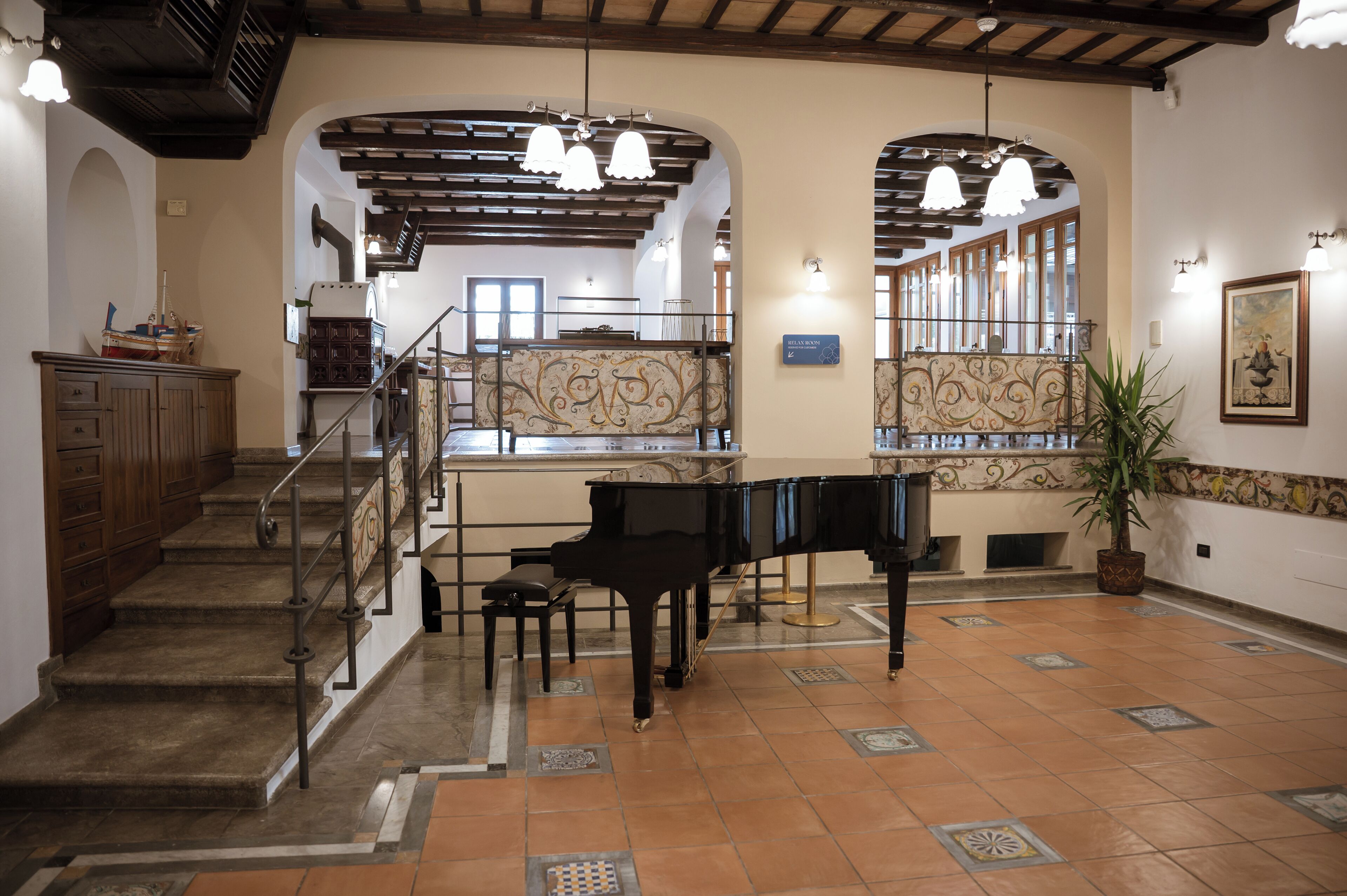 Un'imponente hall con un pianoforte, una scalinata e un'ampia pianta in vaso.