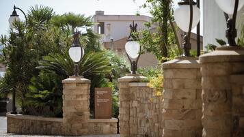 Un espace d’accueil avec une enseigne indiquant la présence d’un restaurant, entouré de piliers en pierre et de lampadaires décoratifs.