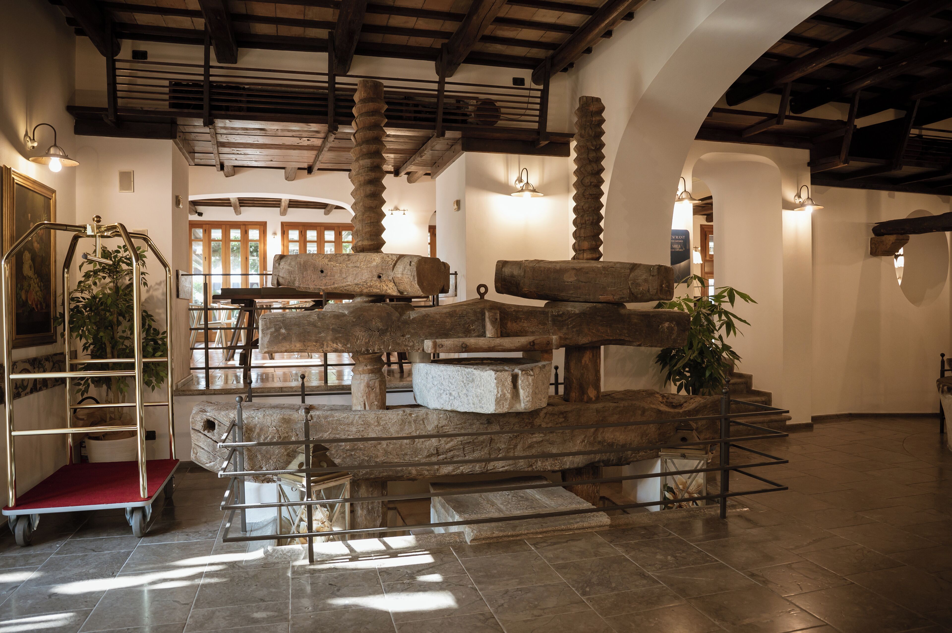 A spacious lobby with a high ceiling, stone columns, and a staircase leading to upper floors.