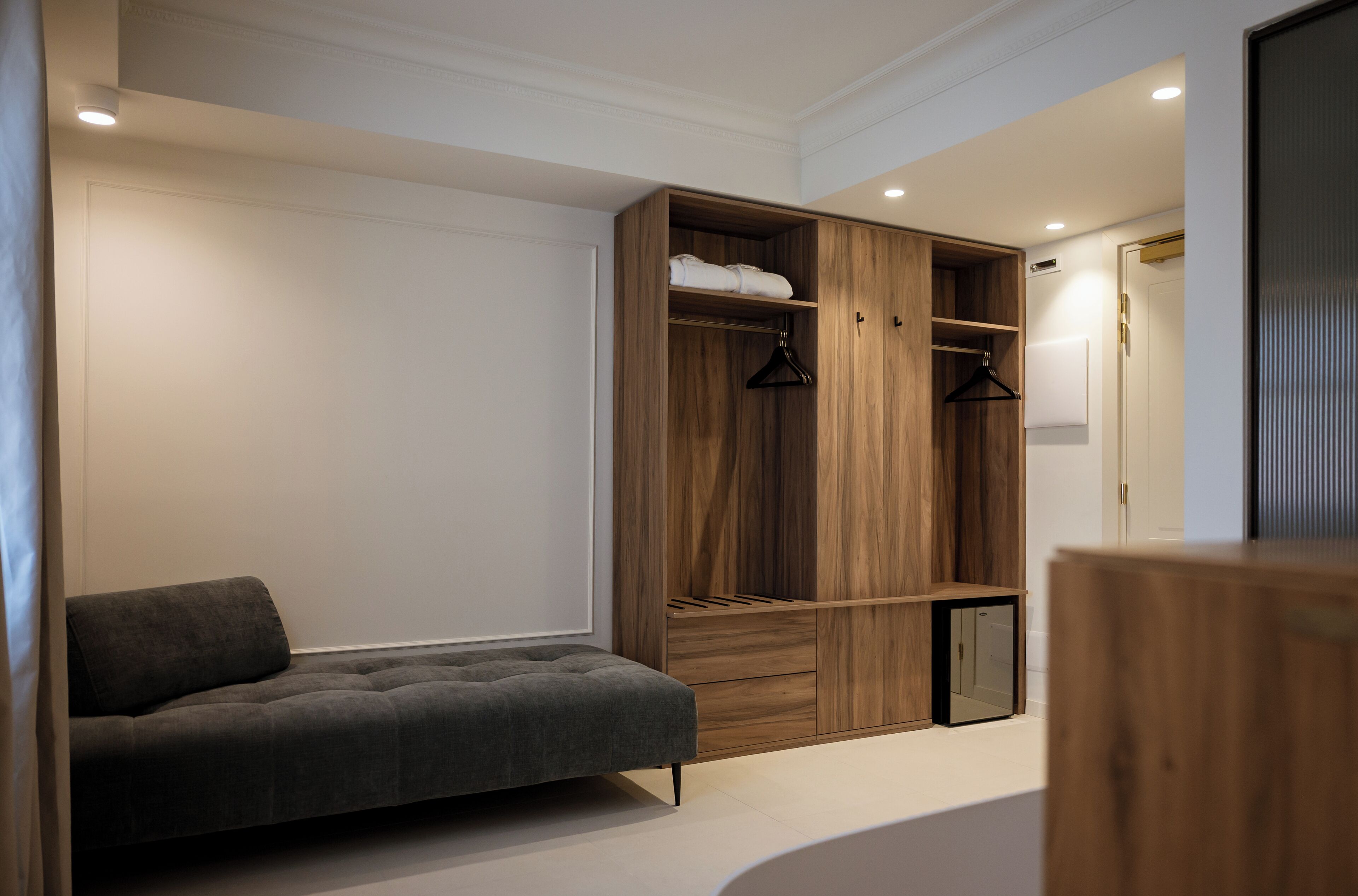 Une chambre moderne avec un canapé gris, une armoire en bois et un petit meuble.