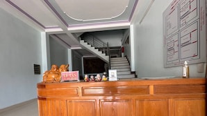 Una recepción con detalles de madera, una escalera que sube a un nivel superior y un diagrama enmarcado en la pared.