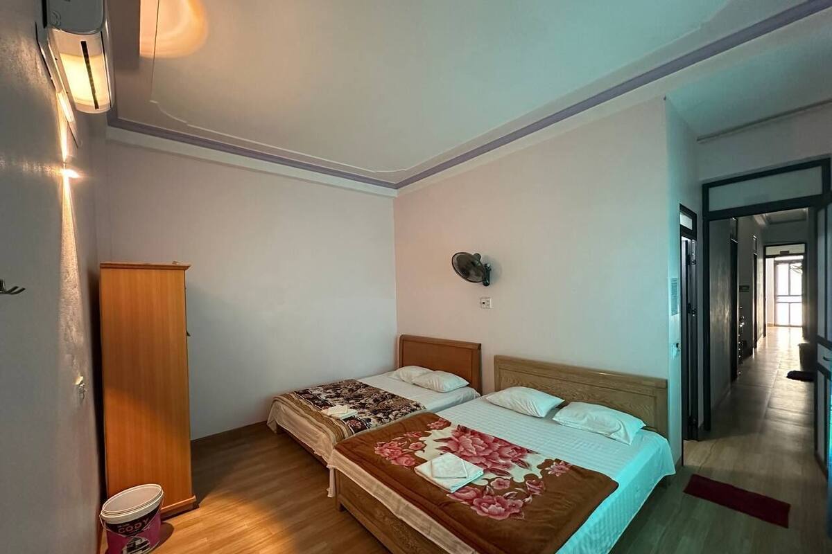 Ein Doppelbett mit floralem Bettbezug, ein Holzschrank und ein Nachttisch mit Lampe.