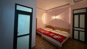 Un dormitorio con cama, una puerta y una lámpara fijada a la pared.