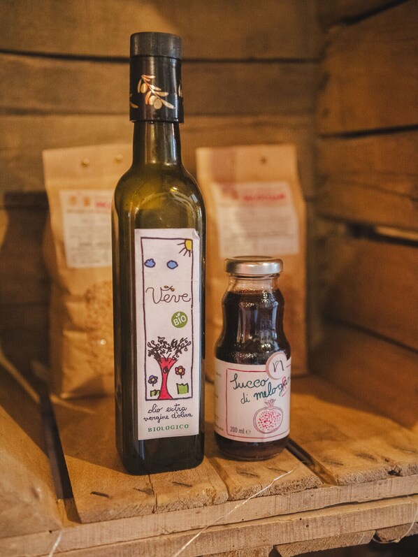Dos botellas de aceite de oliva y un tarro de melaza de granada sobre una superficie de madera.