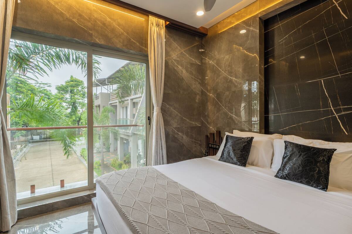 Ein modernes Hotelzimmer mit einem großen Bett, Blick ins Freie und einer Marmorwand.