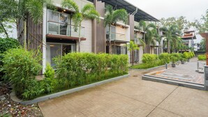 A modern building with multiple floors, large windows, and a covered walkway. - Alaya Stays - Imperial Calista 4BHK near Khandala Hills (Lonavala)