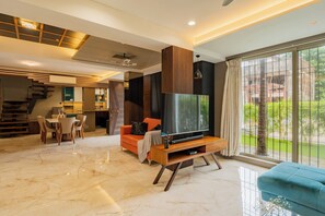 A modern living room with a TV, sofa, and dining area. - Alaya Stays - Imperial Calista 4BHK near Khandala Hills (Lonavala)