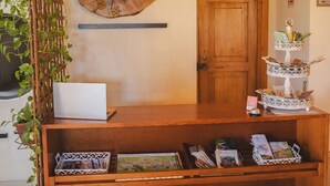 Un mostrador de recepción de madera con una computadora portátil, elementos decorativos en la pared y una puerta al fondo.