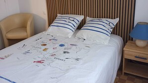 A hotel room with a bed, a chair, a nightstand, and a lamp.