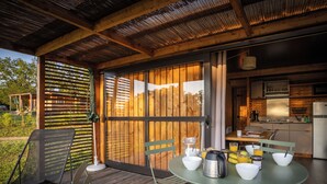 Eine Holzterrasse mit einem Frühstückstisch, komplett mit Schüsseln, einem Wasserkocher und einer Kaffeemaschine.