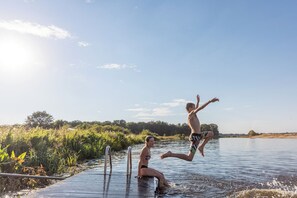 Een houten steiger die uitsteekt in een kalm wateroppervlak, met een heldere lucht erboven.
