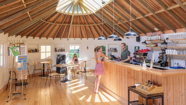 Ein gemütliches Café mit Holzvertäfelung, einer Bar und einer Sitzordnung mit Tischen und Stühlen.