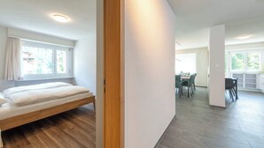 Een moderne kamer met een bed, een eethoek en grote ramen.