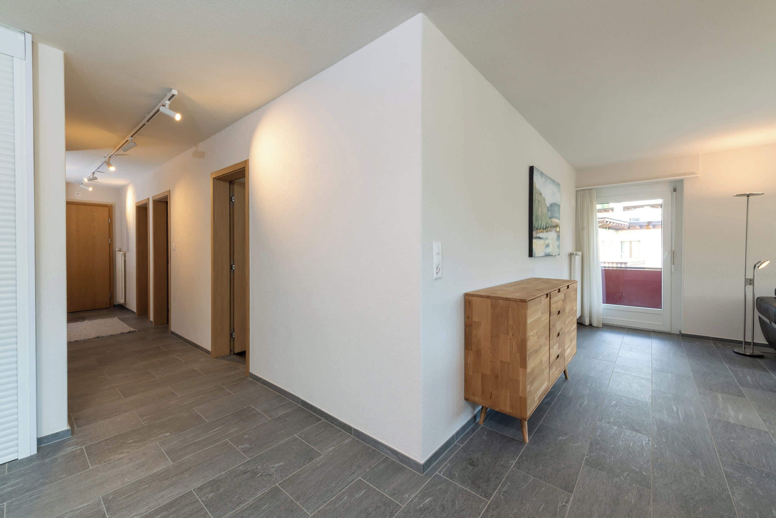 A hallway with a wooden cabinet, a door, and a light fixture.