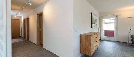 A hallway with a wooden cabinet, a door, and a light fixture.