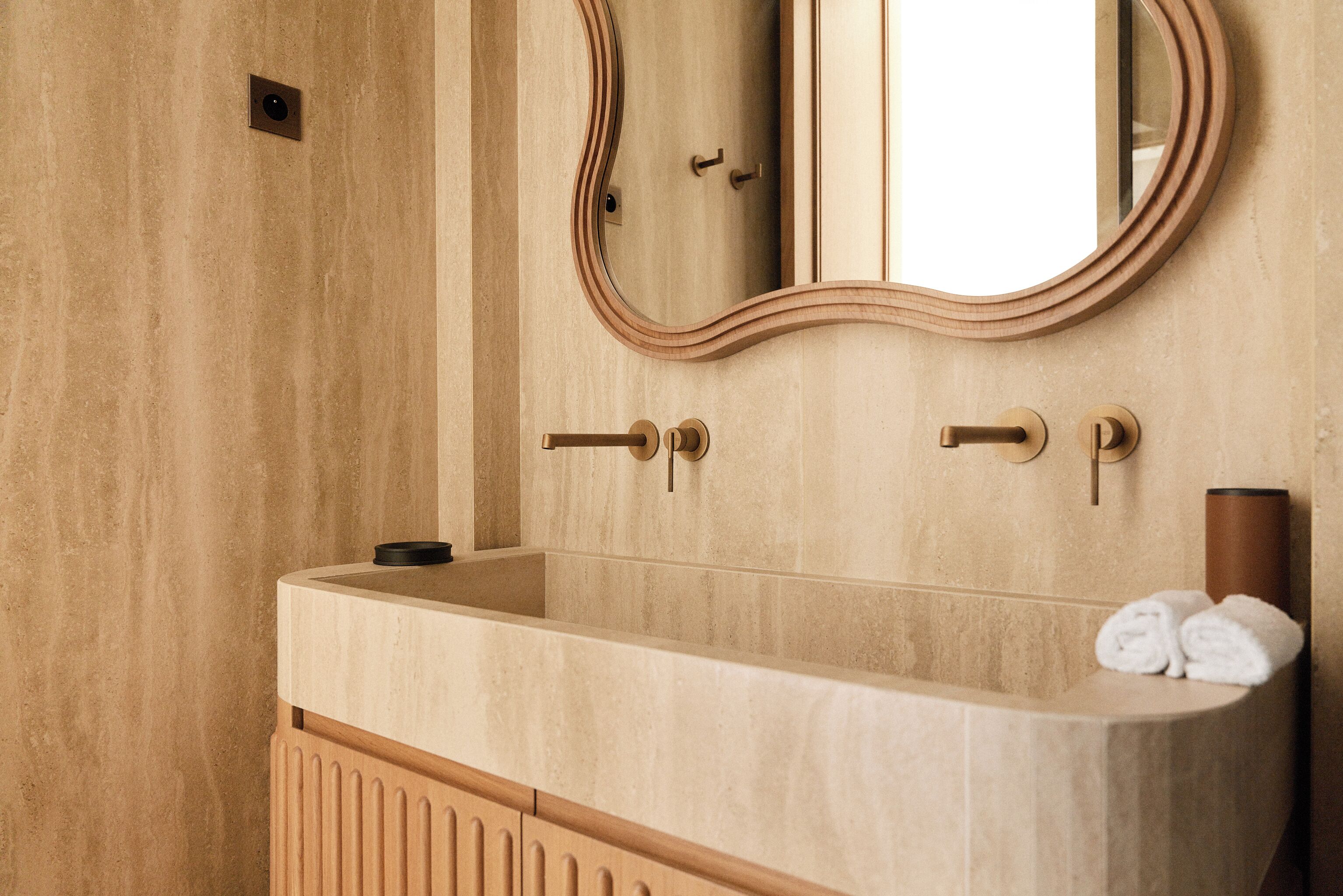 A bathroom with a wooden vanity, a mirror, and a towel rack.