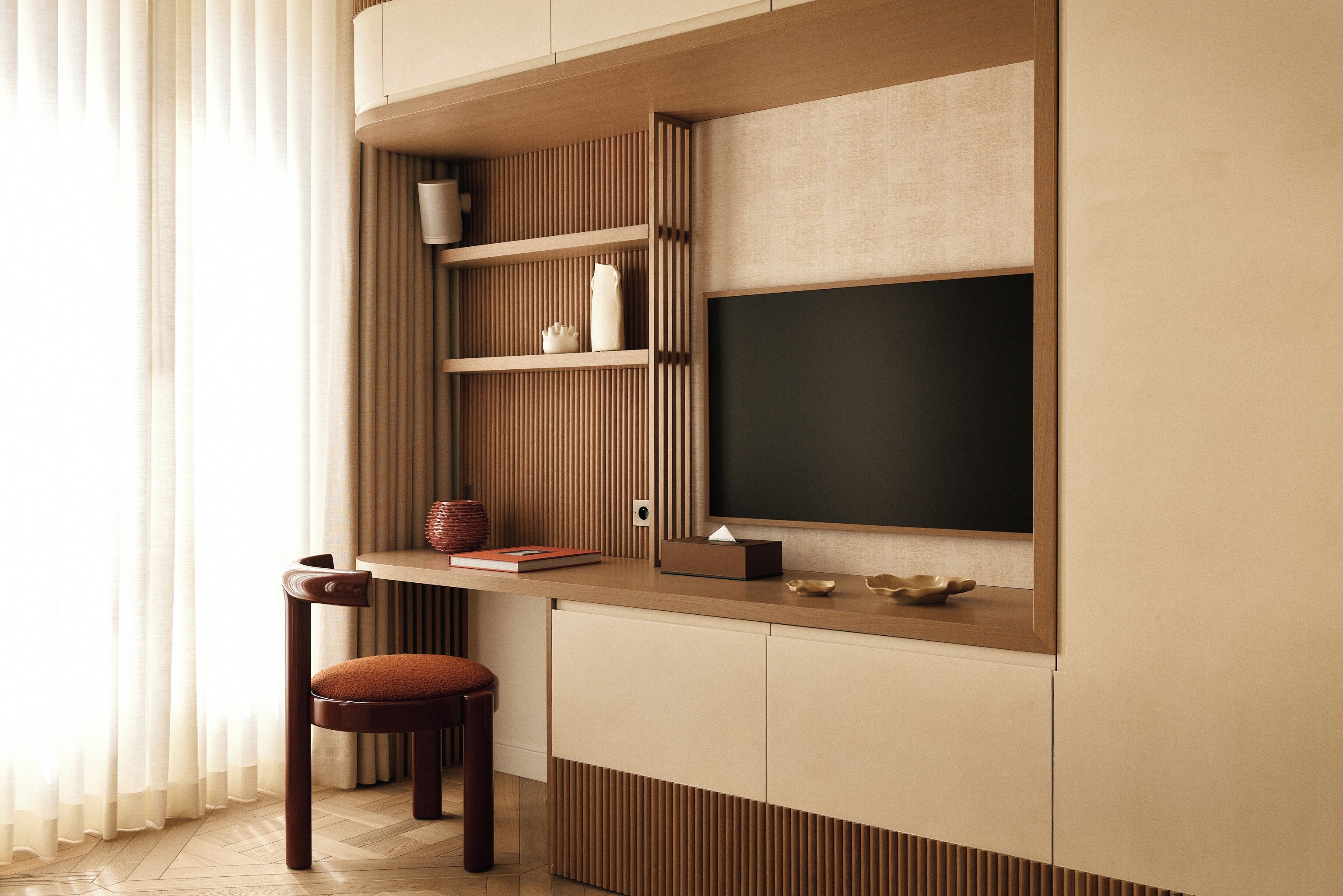 A modern room with a built-in TV, wooden paneling, a cushioned chair, and a small table with a book and decorative items.