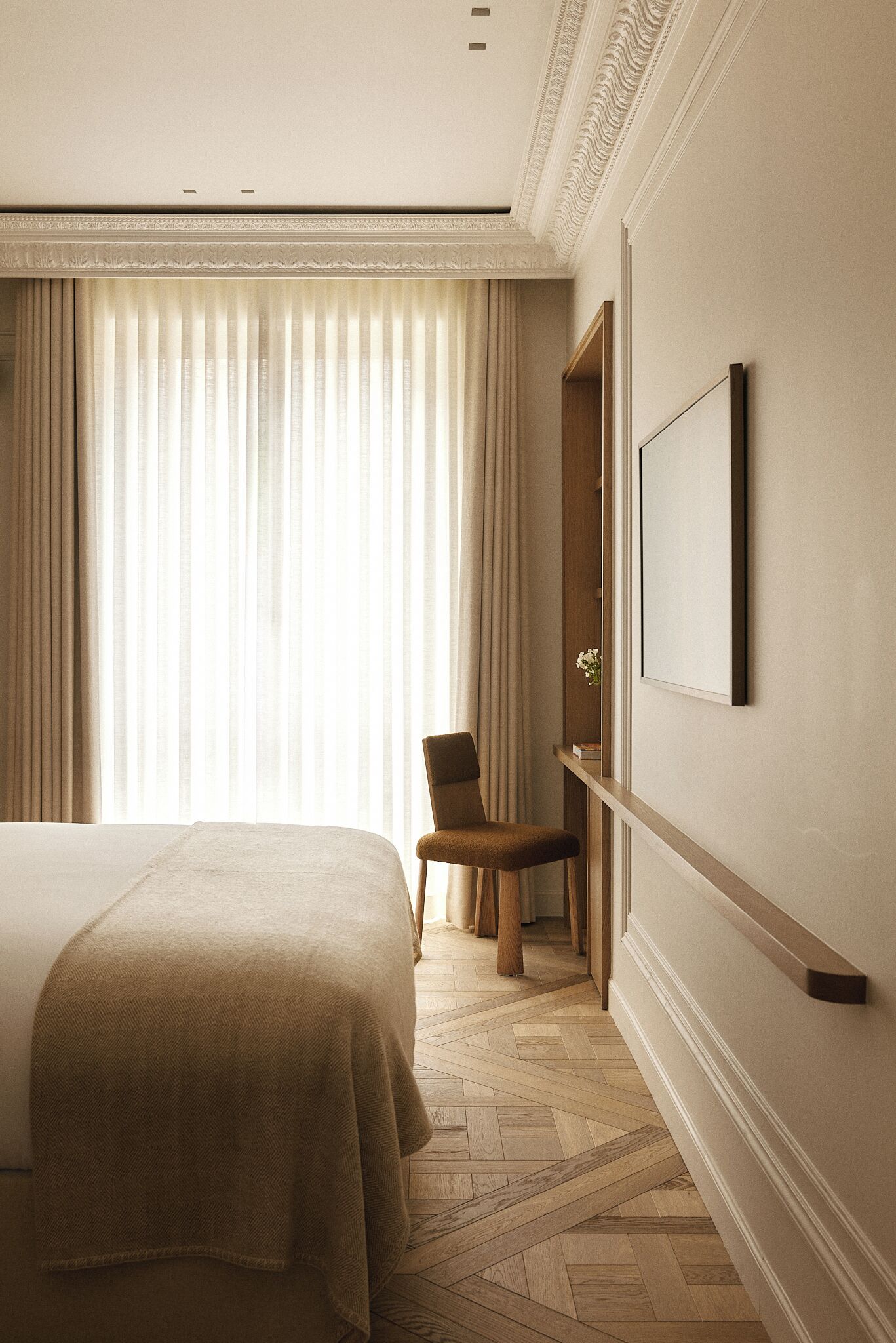 Une chambre d’hôtel avec un grand lit, une chaise, un bureau et une grande fenêtre avec des rideaux.
