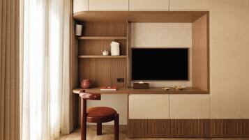 A modern, compact living space with a built-in TV, wooden paneling, a small table, and a cushioned chair.