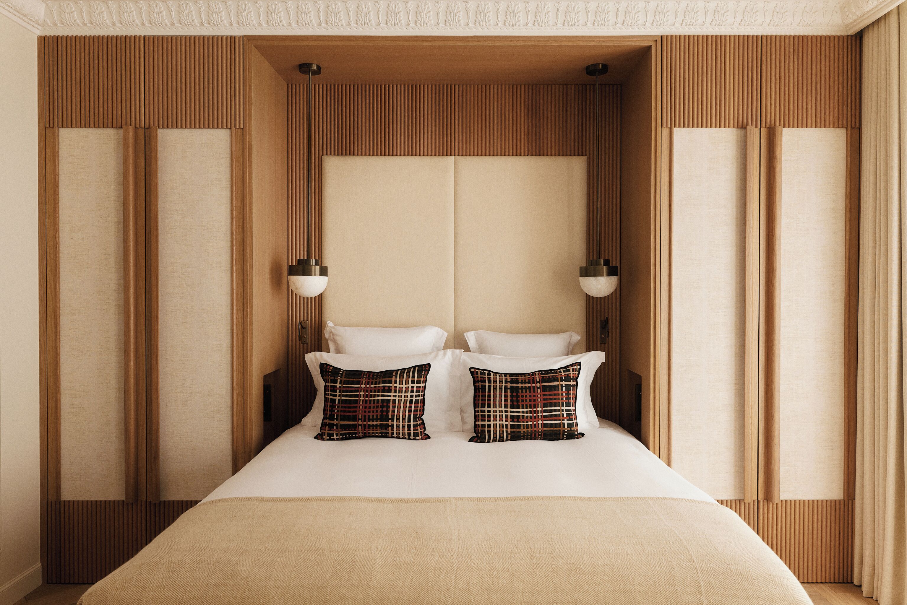 A neatly arranged bedroom with a large bed, two bedside tables, and a headboard with vertical wooden slats.