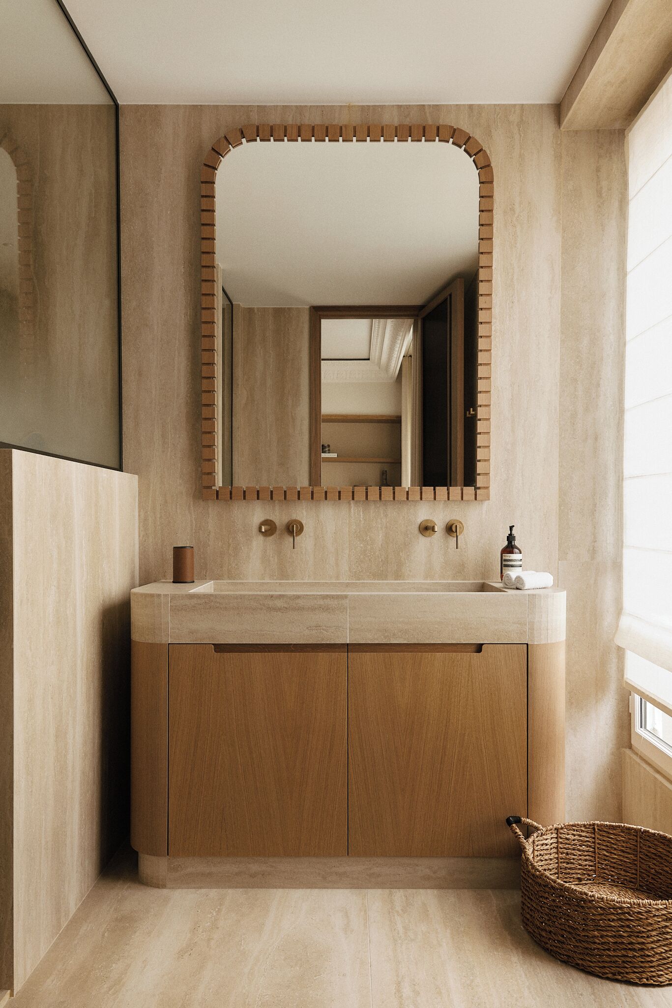 A bathroom with a wooden vanity, a large mirror, and a wicker basket.