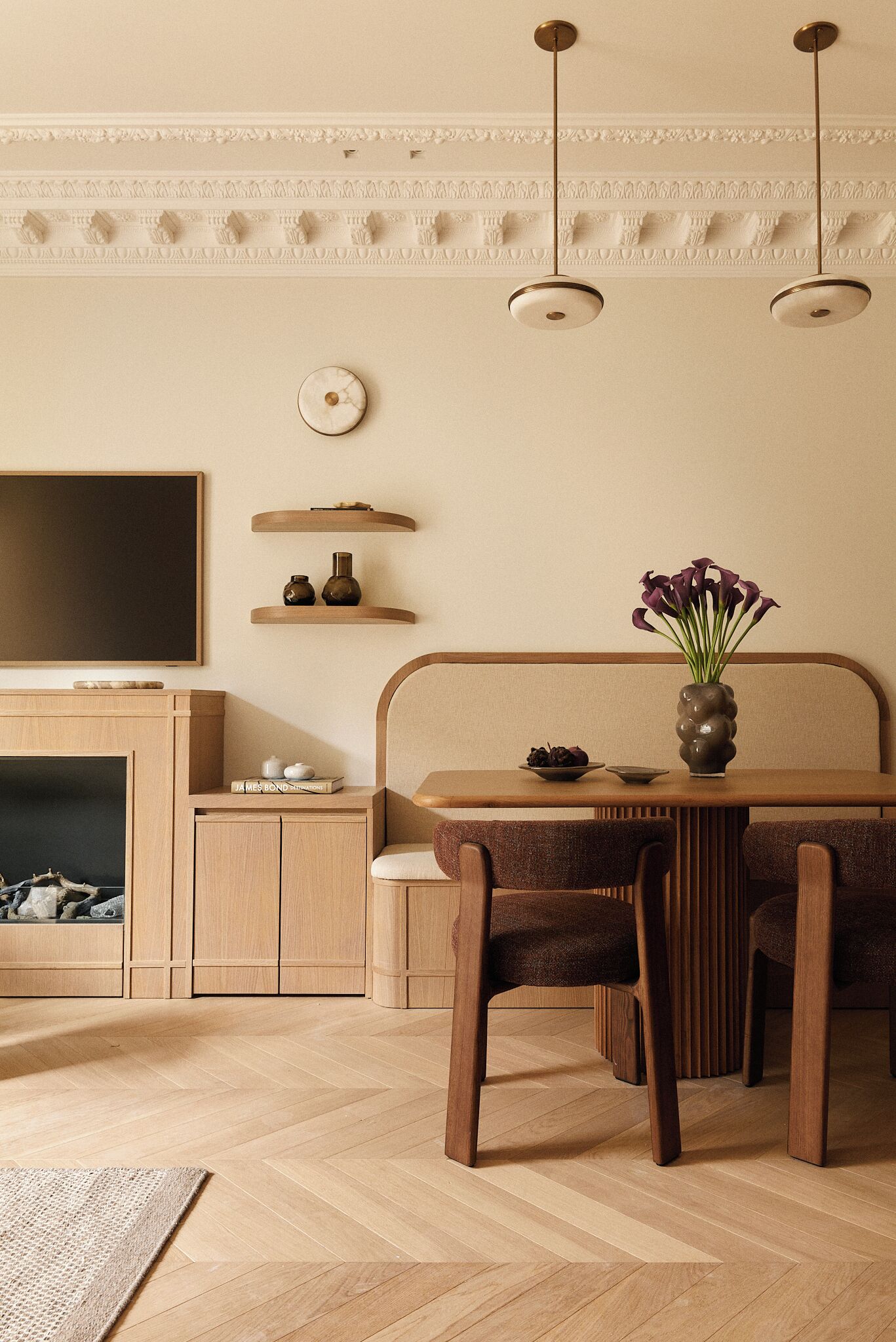 Ein modernes Wohnzimmer mit einem Holzesstisch, zwei Stühlen, einer Couch, einem Fernseher und dekorativen Regalen.