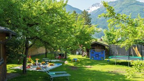 A backyard with a trampoline, picnic table, and play area.