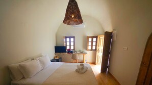 A bedroom with a bed, a desk, a chair, and a hanging light fixture.