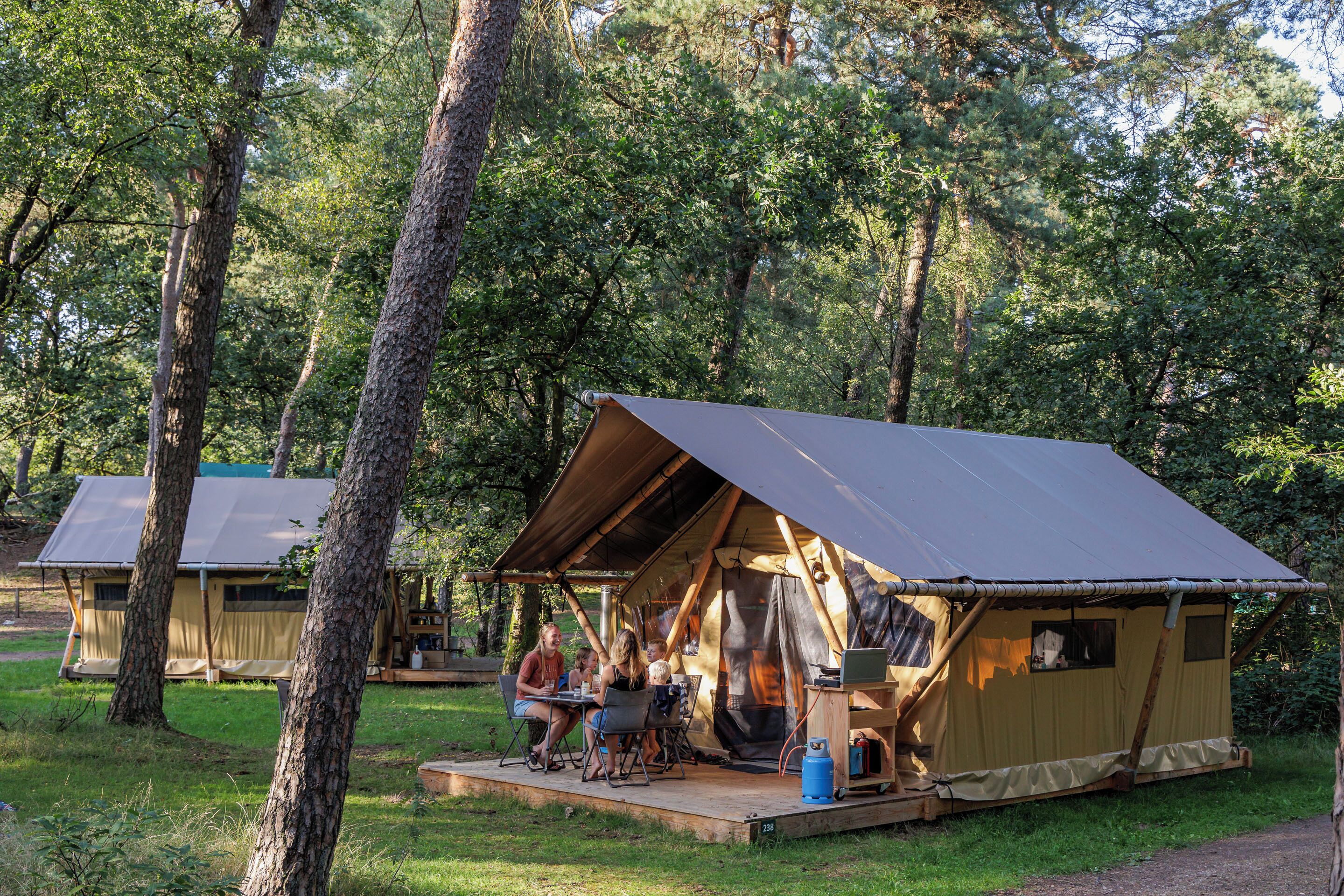 A tented campsite with a dining area and a small table.