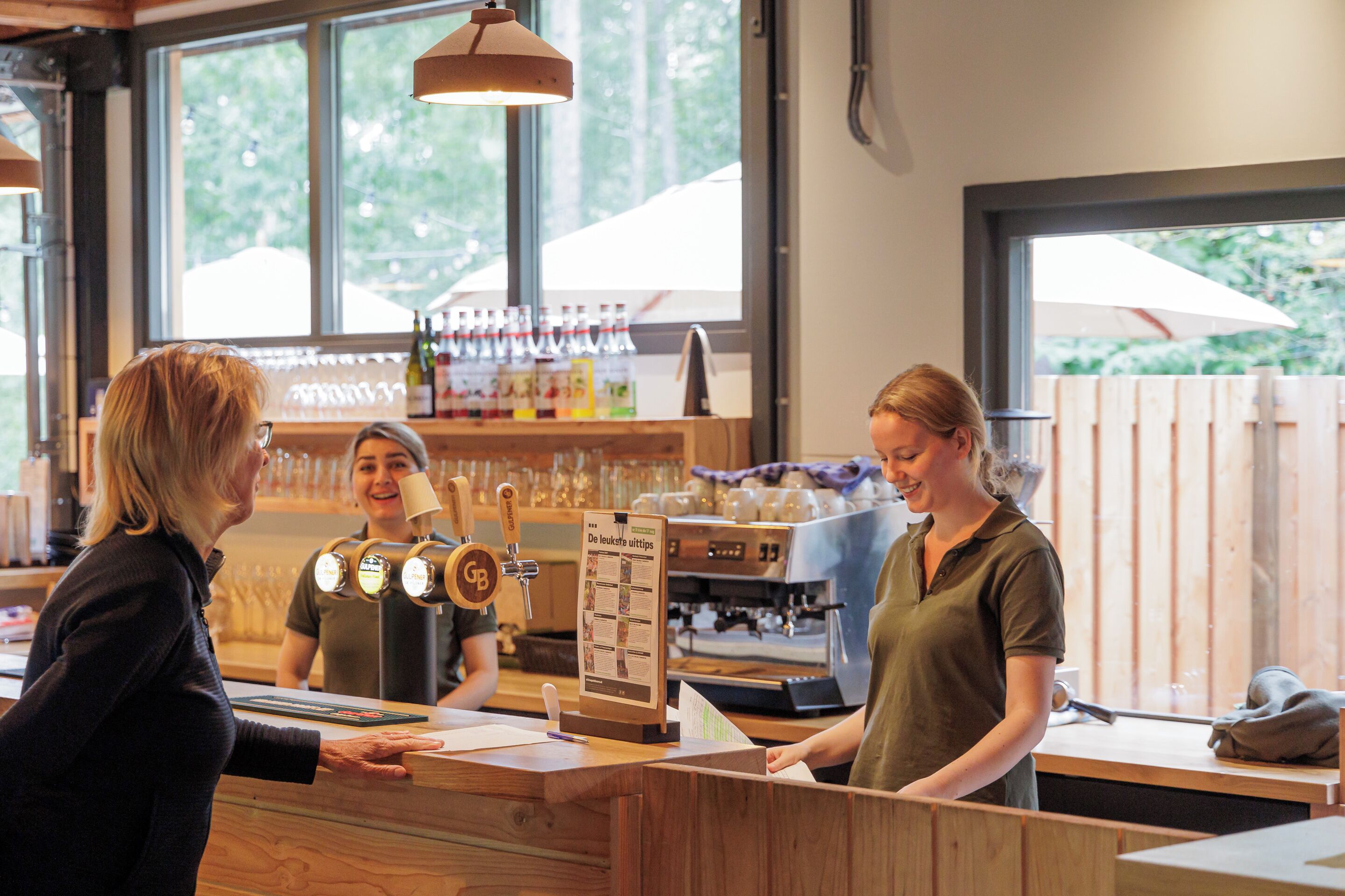Interieur van een koffietent met een houten toonbank, een koffieapparaat en een menubord.