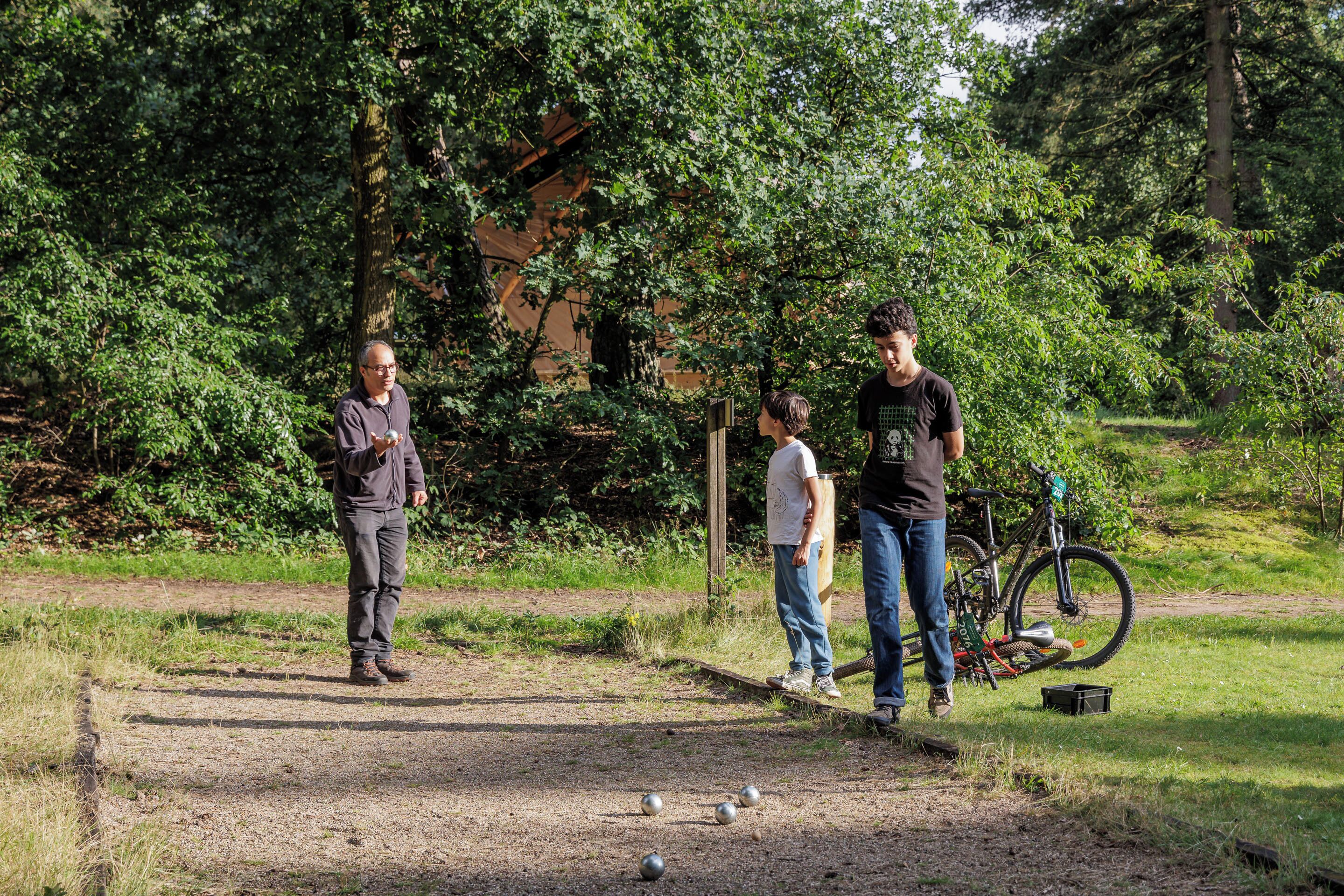 Un grupo de personas jugando croquet en un parque con árboles y una bicicleta al fondo.