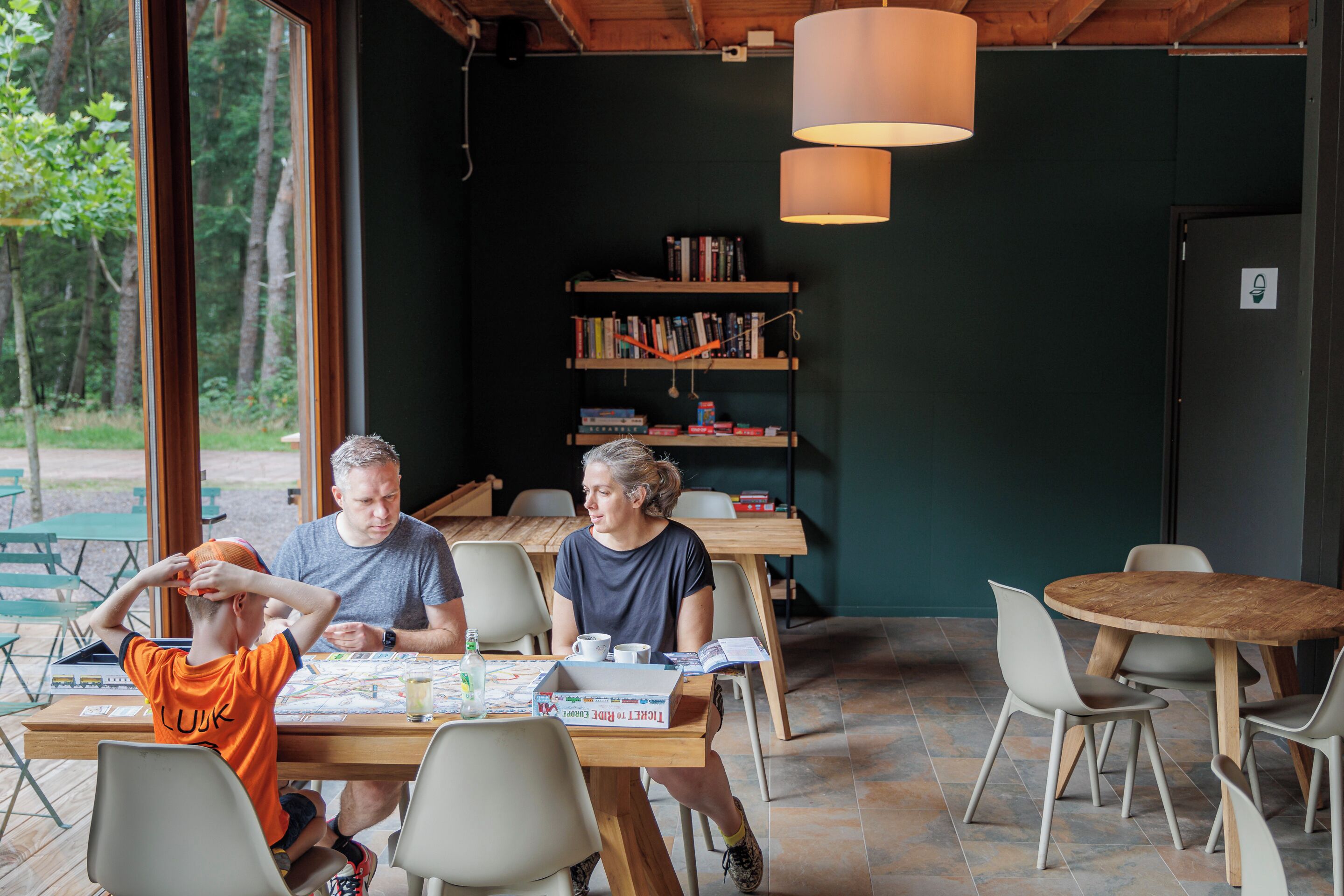 A dining area with a wooden table, chairs, and a bookshelf in the background.