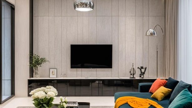 A modern living room with a large flat-screen TV mounted on a wooden wall, a sofa with colorful cushions, a coffee table with a vase of flowers, and a floor lamp.