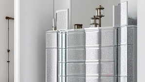A mirrored wardrobe with a metallic finish and a mirrored cabinet below.