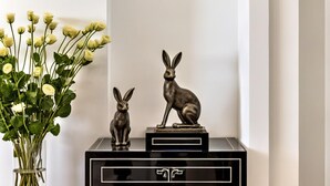 A black console table with two rabbit figurines and a vase of white flowers.