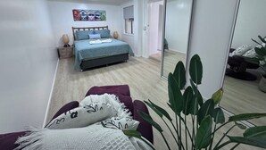 A modern bedroom with a bed, bedside tables, a mirror, and a plant.