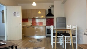 Une cuisine moderne avec des meubles en bois, un four encastré, un réfrigérateur et un coin repas comprenant une table et des chaises.