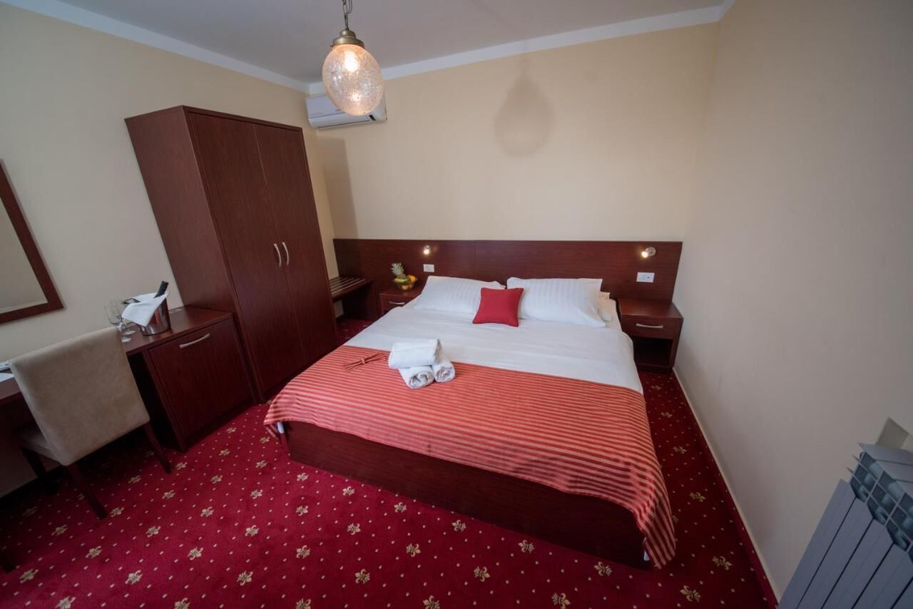 Una habitación de hotel con una cama grande, un armario, un escritorio y una mesita de noche.