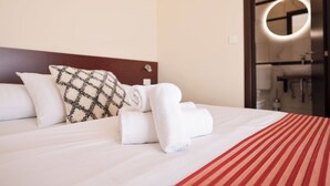 A neatly made bed with white linens and a red-striped bedspread, a patterned pillow, and a rolled-up towel. - Villa Anton B&B (Sukošan)