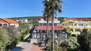 A residential area with houses featuring red-tiled roofs and a central building with a glass facade. - Villa Anton B&B (Sukošan)