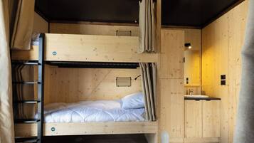 Habitación con literas, un lavamanos pequeño y un espejo.