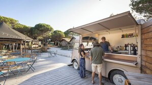 A food truck with a canopy, serving area, and beverage bottles. - Huttopia Lagoa de Obidos  (Obidos)