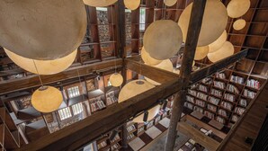 Un interno in legno su più livelli, con scaffali e lampade sferiche sospese.