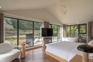 A modern bedroom with a large bed, a TV, and a view of a lush garden. - JinSpecial Gaotian (Quzhou)