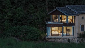 Eine zweistöckige Holzhütte mit Balkon, großen Fenstern und einem Steinfundament.