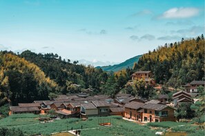 A cluster of traditional-style buildings with sloped roofs, surrounded by lush greenery and mountains in the background. - JinSpecial Gaotian (Quzhou)