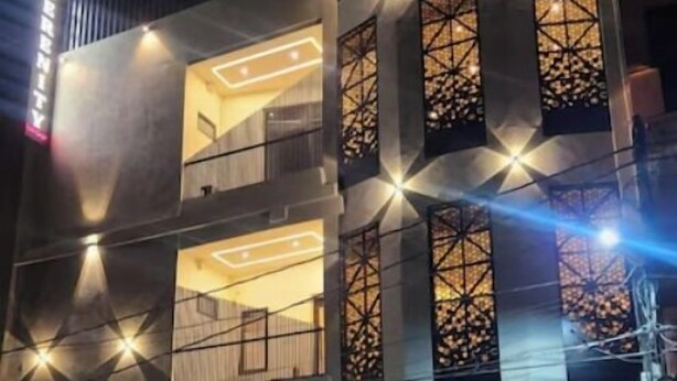 A multi-story building with illuminated windows and balconies, a visible entrance, and a staircase leading to the entrance. - Serenity By The Ganges (Haridwar)
